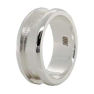 May include: A silver ring with a wide band and a textured surface. The ring is marked with the number "925".