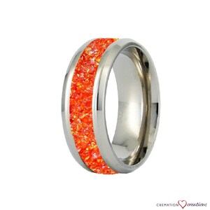 May include: A stainless steel ring with a band of orange crystals.