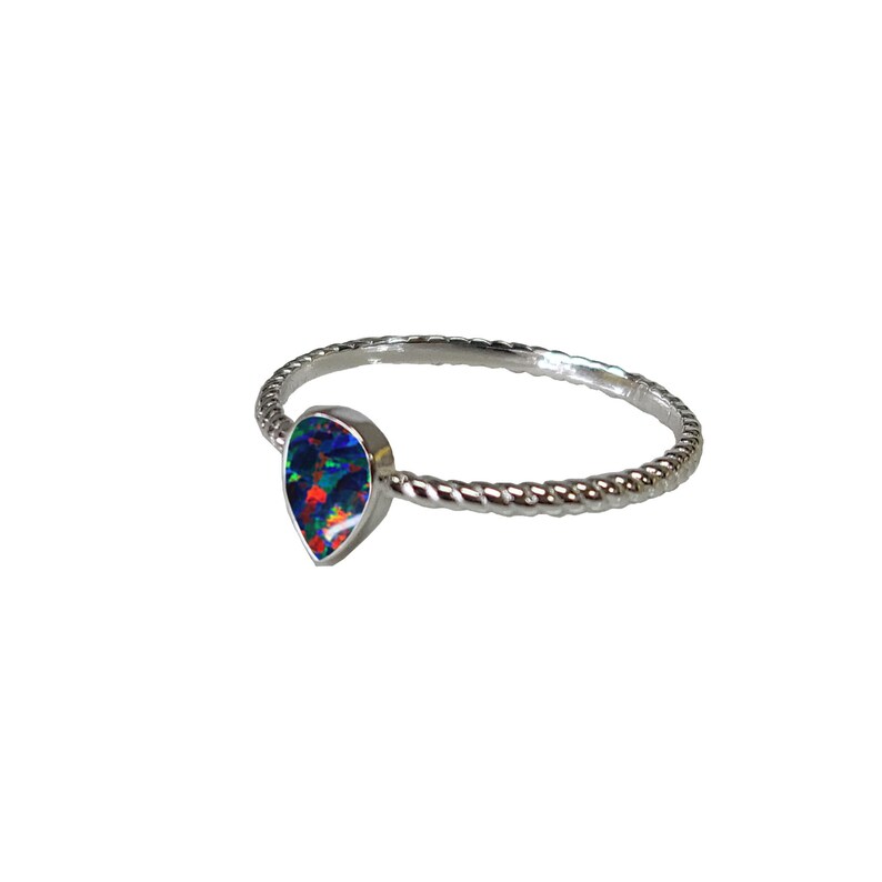 May include: A silver ring with a teardrop-shaped opal gemstone. The ring has a twisted band.