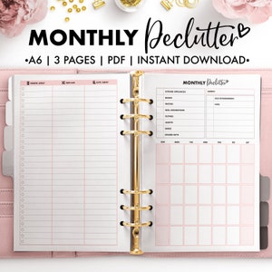 Op de afbeelding: Een roze en witte printbare planner met de titel "MONTHLY Declutter" en een hartje. De planner heeft secties voor "Throw Away", "Replace", "Give Away", "Kitchen Appliances", "Books", "Photos", "Wall Decorations", "Clothes", "Shoes", "Unused Gifts" en een maandelijkse kalender.