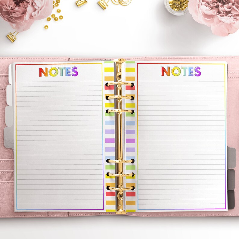 May include: An open planner with a rainbow striped spine and the word "NOTES" in rainbow letters on each page.