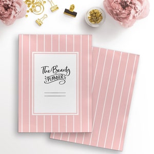 May include: A pink and white striped notebook with the text "The Beauty Planner" on the front cover.