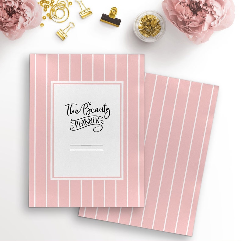 May include: A pink and white striped notebook with the text "The Beauty Planner" on the front cover.