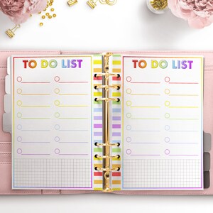 May include: A rainbow-colored to-do list planner with a gold binder. The planner has two pages with the text "TO DO LIST" at the top of each page. Each page has a grid pattern and a list of circles with lines next to them.