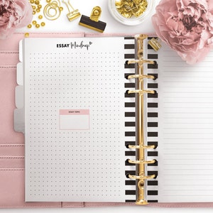 May include: A white planner with black and white striped pages and a gold ring binder. The planner has a dotted page with a pink box labeled "Essay Topic" and the words "Essay Mindmap" written in black at the top of the page.