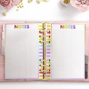 May include: An open planner with two pages labeled "NOTES" in rainbow letters. The pages are lined with a grid pattern and have a rainbow colored divider.