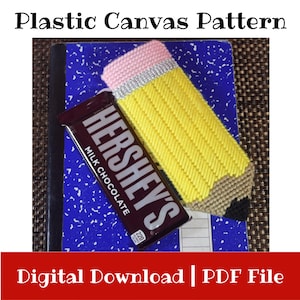 Op de afbeelding: Een geel, roze en zilver potloodvormig plastic canvas patroon, met een Hershey's Milk Chocolate reep op een blauw notitieboek. De tekst "Plastic Canvas Pattern" en "Digital Download | PDF File" zijn zichtbaar.