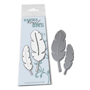 May include: Feather-shaped metal dies in a clear plastic package. The package has the text "Karten Kunst Dies" and "www.karten-kunst.de". The dies are silver and white, and are suitable for card making and scrapbooking.