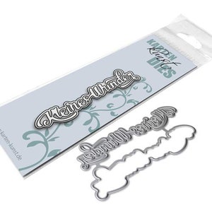 May include: A metal die-cut set featuring the cursive words "Kleines Wunder" with a white outline, presented on a light blue background. The set includes the die-cut word and its outline. The packaging is visible.