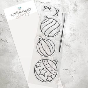 Könnte beinhalten: Transparente Stempelplatte mit vier Weihnachtsbaumschmuck-Designs. Die Ornamente sind in Schwarz umrandet und haben verschiedene Muster, darunter Streifen, Wirbel und Sterne.