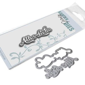 May include: A silver metal die-cut with the words "Alles Liebe" in a cursive font. The die-cut is packaged in a clear plastic bag with a white card that says "KARDEN DIES" in black text.