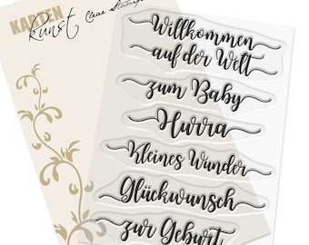 May include: Clear stamp set with six different phrases in German: Willkommen auf der Welt, zum Baby, Hura, Kleines Wunder, Glückwunsch, zur Geburt. The stamps are on a white background.