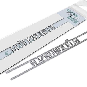 May include: A metal die cut for crafting, featuring the words "glückwunsch" (congratulations) in a decorative font. The die cut is shown on a white background with the brand name "KARDEN KRAFT DIES" in the top right corner.