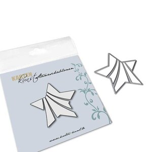 May include: A silver star-shaped stencil with a geometric design, alongside its packaging. The stencil has white interior sections. The packaging is light blue with a floral design and text.