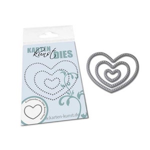 May include: A silver metal die cut in the shape of a heart with three concentric circles. The die cut is on a white background with a blue and green floral design and the text "Karten Kunst Dies".