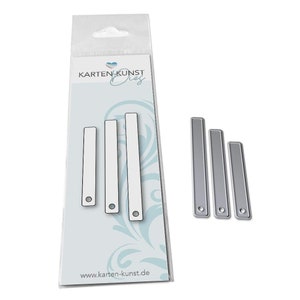 Könnte beinhalten: Ein Satz von vier Metallstanzformen in Form von rechteckigen Streifen mit einem kleinen Kreis, der oben ausgeschnitten ist. Die Streifen sind in abgestufter Größenordnung angeordnet, wobei der größte Streifen links und der kleinste Streifen rechts liegt. Die Streifen sind silberfarben und haben eine glänzende Oberfläche. Die Stanzformen sind in einem durchsichtigen Plastikbeutel mit einem weißen Kartenrücken verpackt, auf dem "Kartenkunst Dies" und "www.karten-kunst.de" steht.