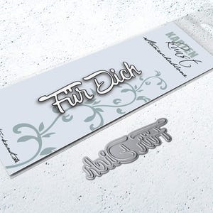 May include: A metal die cut with the words "Für Dich" in a cursive font. The die cut is on a white background with a floral design.