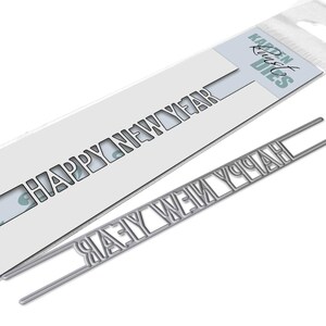 Könnte beinhalten: Eine silberne Metallstanze zum Basteln. Die Stanze schneidet die Worte "Happy New Year" in Bannerform aus. Die Stanze ist in einer durchsichtigen Plastiktüte mit einem weißen Etikett verpackt, auf dem "Karen Burst Dies" steht.