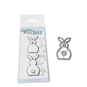 May include: A set of three metal die cuts in the shape of a bunny rabbit. The die cuts are designed for crafting and scrapbooking. The die cuts are on a white background with the text "Karten Kunst Dies" printed on the background.