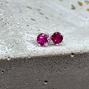 Könnte beinhalten: Ein Paar silberne Ohrstecker mit leuchtend pinkfarbenen Edelsteinen.