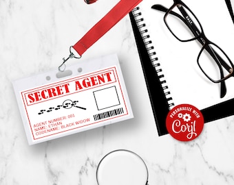 May include: A white plastic ID card with red text that reads "SECRET AGENT". The card has a black and white illustration of a magnifying glass and footprints. The card also has the text "AGENT NUMBER: 001", "NAME: ETHAN", and "CODENAME: BLACK WIDOW".