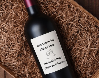 May include: A black wine bottle with a white label that reads "Das Leben ist viel zu kurz, um schlechten Wein zu trinken". The bottle is sitting in a brown paper shred basket.