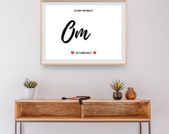 Op de afbeelding: Een witte ingelijste print met zwarte tekst die "Du bist die Beste Om Ich liebe dich" zegt met twee rode harten. De print hangt aan een witte muur boven een houten tafel.