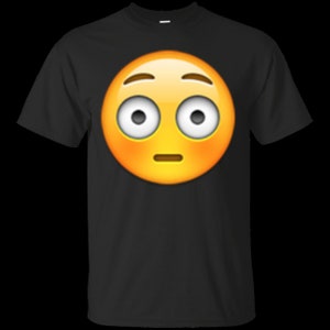 May include: A black t-shirt with a yellow emoji face with wide eyes and a slightly open mouth. The emoji is expressing confusion or surprise.