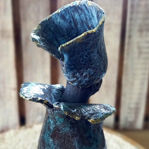May include: A ceramic vase with a blue and green glaze and gold accents. The vase is shaped like a flower with a wide opening at the top.