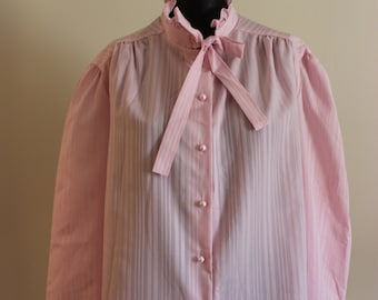 May include: A pink striped blouse with a ruffled collar and a bow tie. The blouse has pearl buttons down the front.
