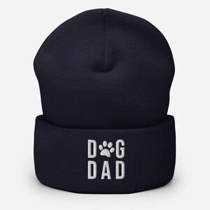 May include: Navy blue beanie with a white embroidered paw print and the text "DOG DAD".