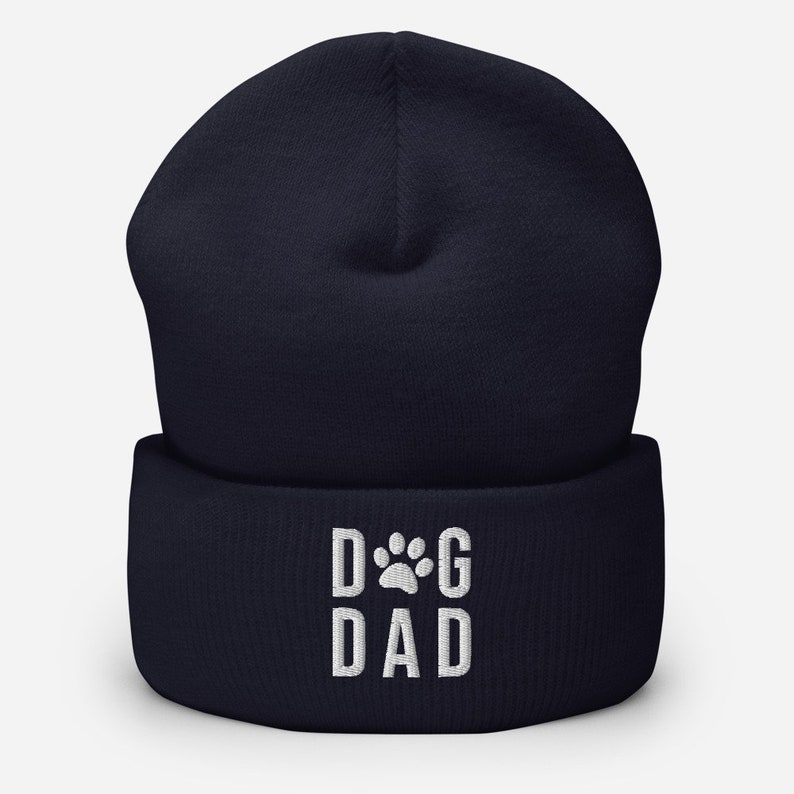 May include: Navy blue beanie with a white embroidered paw print and the text "DOG DAD".