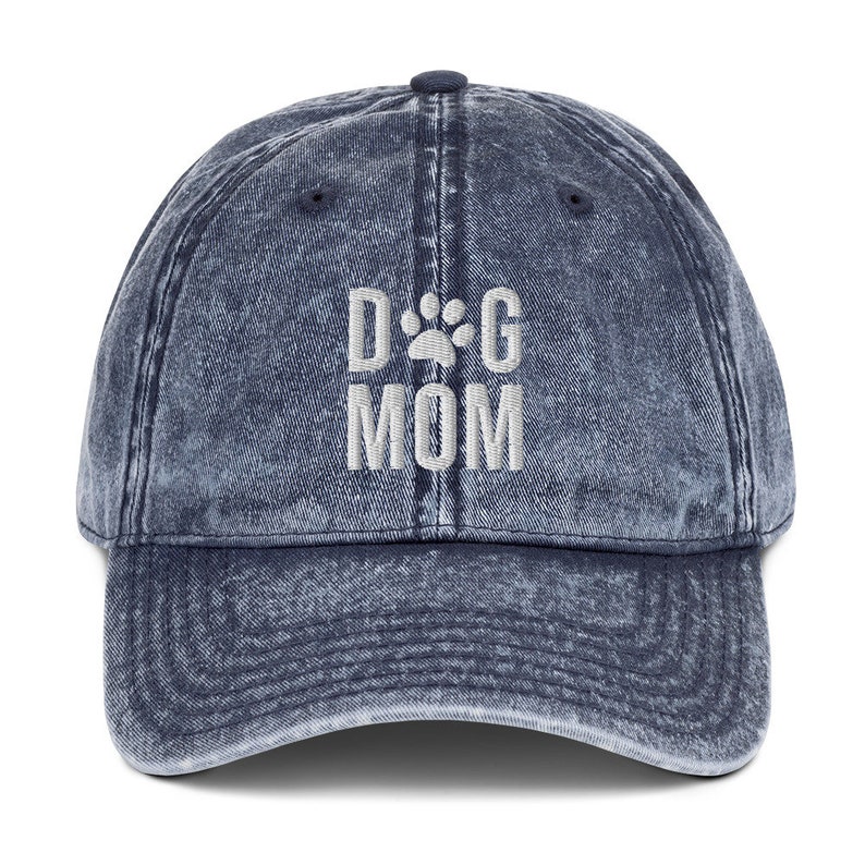 May include: A blue denim baseball cap with the text "DOG MOM" embroidered in white with a paw print in place of the "O".