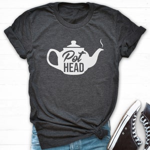 May include: A dark gray t-shirt with a white teapot graphic and the text "Pot Head" printed on the front.