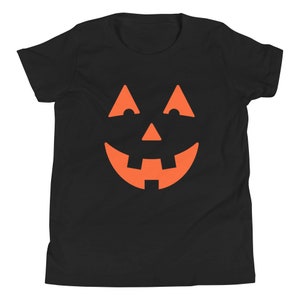 Puede incluir: Camiseta negra para ni&ntilde;os con un gr&aacute;fico de cara de calabaza naranja.