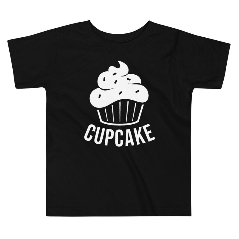 May include: Black toddler t-shirt with a white cupcake graphic and the word "CUPCAKE" printed below it.