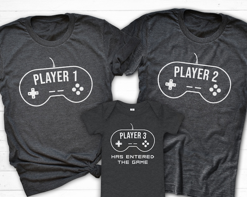 May include: Three gray t-shirts with a video game controller graphic and the text "Player 1", "Player 2", and "Player 3 has entered the game".