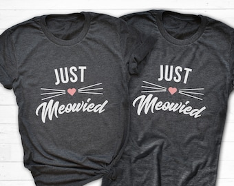 May include: Two dark gray t-shirts with the text "Just Meowed" in white with a pink heart and white whiskers.