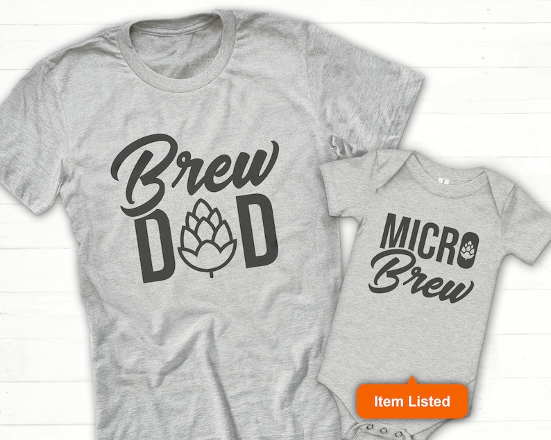 K&ouml;nnte beinhalten: Ein graues T-Shirt mit dem Text "Brew Dad" und einer Hopfengrafik. Ein grauer Baby-Strampler mit dem Text "Micro Brew" und einer Hopfengrafik.