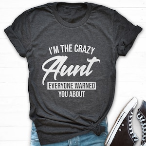 Könnte beinhalten: Ein dunkelgraues T-Shirt mit dem Aufdruck "I'm the crazy Aunt everyone warned you about" in weiß.