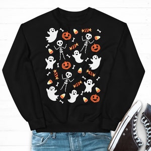 K&ouml;nnte beinhalten: Schwarzer Pullover mit einem Halloween-Motiv mit Geistern, Skeletten, Mais und K&uuml;rbissen.