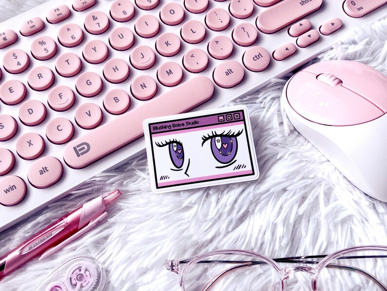 May include: A pink keyboard with round keys, a pink mouse, a pink pen, clear glasses and a sticker with a cartoon illustration of a pair of eyes with stars and hearts. The sticker reads "Blushing Boba Studio".