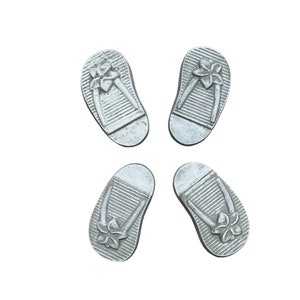 May include: Four silver flip-flop shaped decorative items with a flower design.
