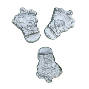 Puede incluir: Tres peque&ntilde;as figuritas de Pap&aacute; Noel de hormig&oacute;n gris. Cada figurita tiene una pose y una expresi&oacute;n facial diferentes.