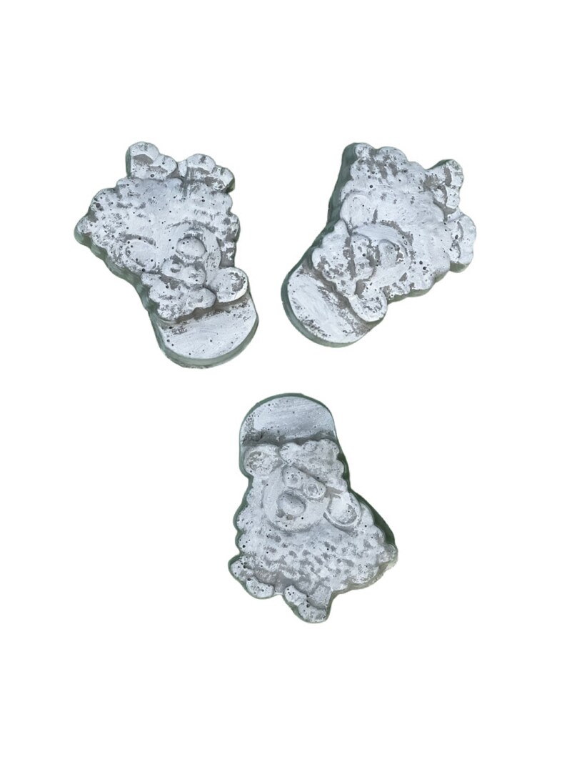 Puede incluir: Tres peque&ntilde;as figuritas de Pap&aacute; Noel de hormig&oacute;n gris. Cada figurita tiene una pose y una expresi&oacute;n facial diferentes.