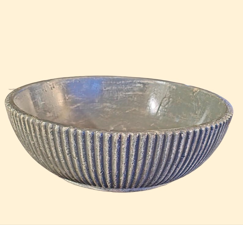 May include: A gray ceramic bowl with a ribbed design. The bowl is round and has a smooth, slightly textured surface.