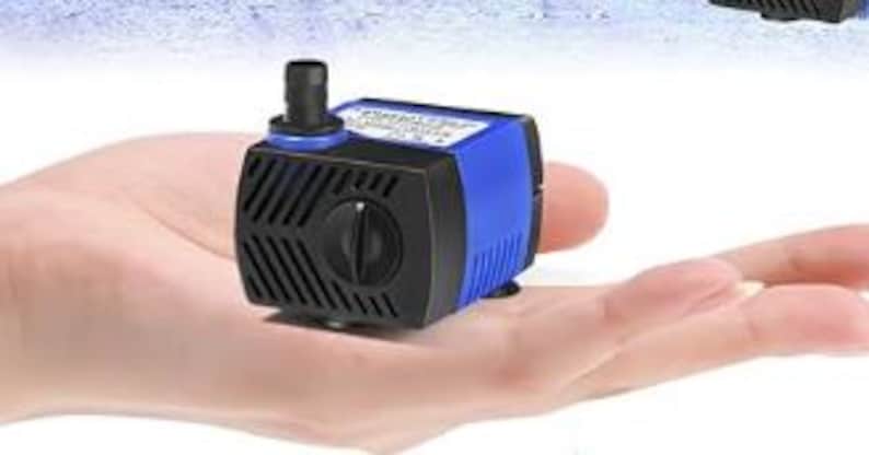 May include: A small blue and black submersible water pump with a black knob on the side. The pump has a clear plastic hose attached to the top.