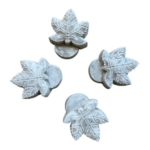 May include: Four gray leaf-shaped ceramic knobs with a whitewash finish. The knobs are mounted on a round base.