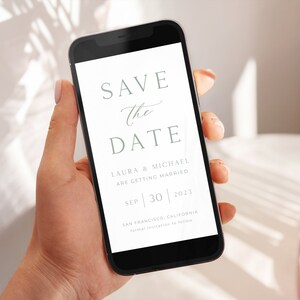May include: A white save the date card on a smartphone screen. The card says "Save the Date" with the names Laura & Michael, the date September 30, 2023, and the location San Francisco, California.