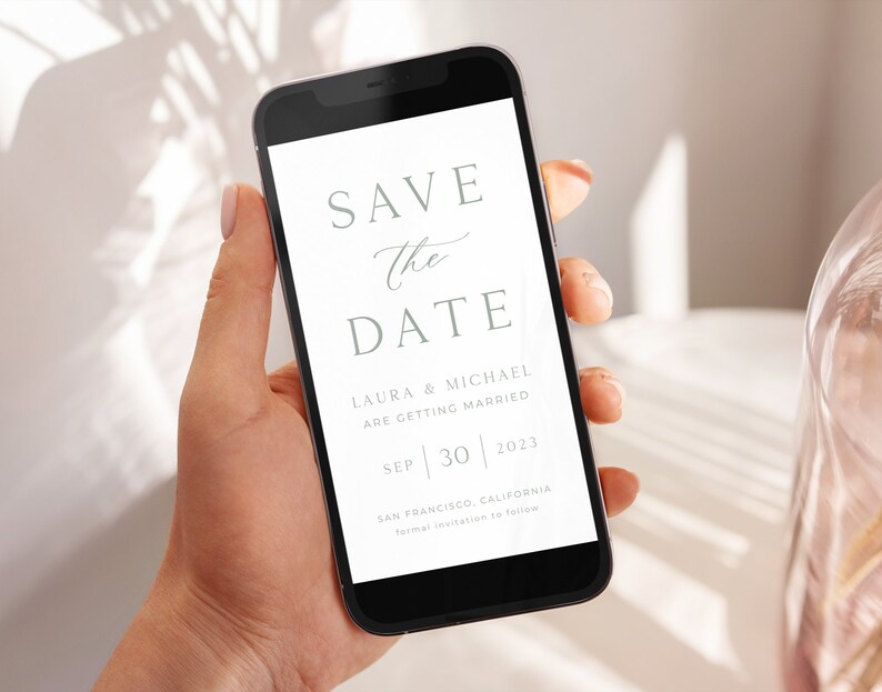 May include: A white save the date card on a smartphone screen. The card says "Save the Date" with the names Laura & Michael, the date September 30, 2023, and the location San Francisco, California.